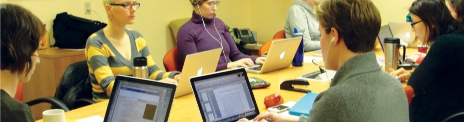 Students sitting at a table working on their laptops. 