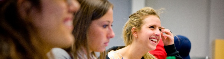 Three students in class. One is smiling largely. 