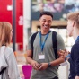 Group Of College Student Friends Meeting And Talking In Busy Communal Campus Building. 