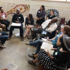 group of people sitting in a room, having a discussion. 