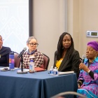 Yaide Valdez, Louisa Fletcher-Pacheco, and Anyango Kamina listening to Karima Amin speak during the plenary panel at the Women's History Month symposium. 