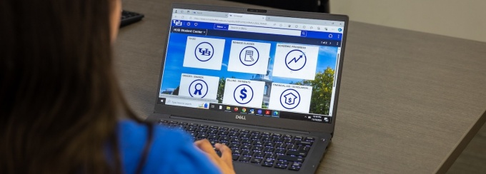 Person looking at laptop with HUB student center icons on screen. 