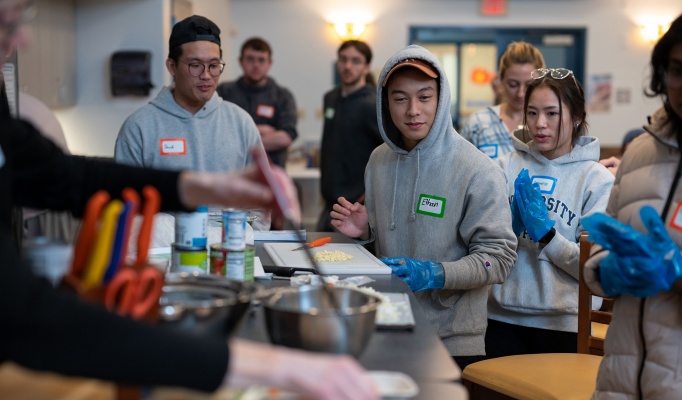 A group of students learning how to cook a meal together in the South Lake Village community room. 