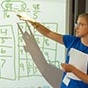 Student pointing at a math problem on a large screen. 