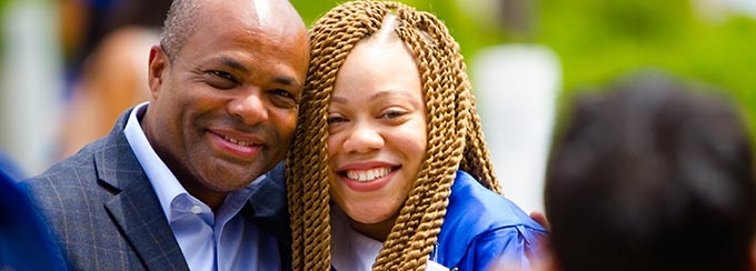 Father and daughter hugging and smiling at a graduation ceremony. 