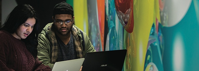 Two students with laptops studying in Lockwood Library. 