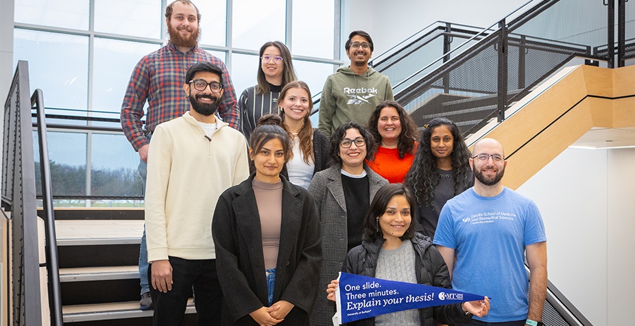 Group photo of 2024 3MT competition participants on a staircase in One World Cafe on the University at Buffalo North Campus. 