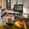 A researcher in a lab coat loads a biological sample into a piece of lab equipment. 